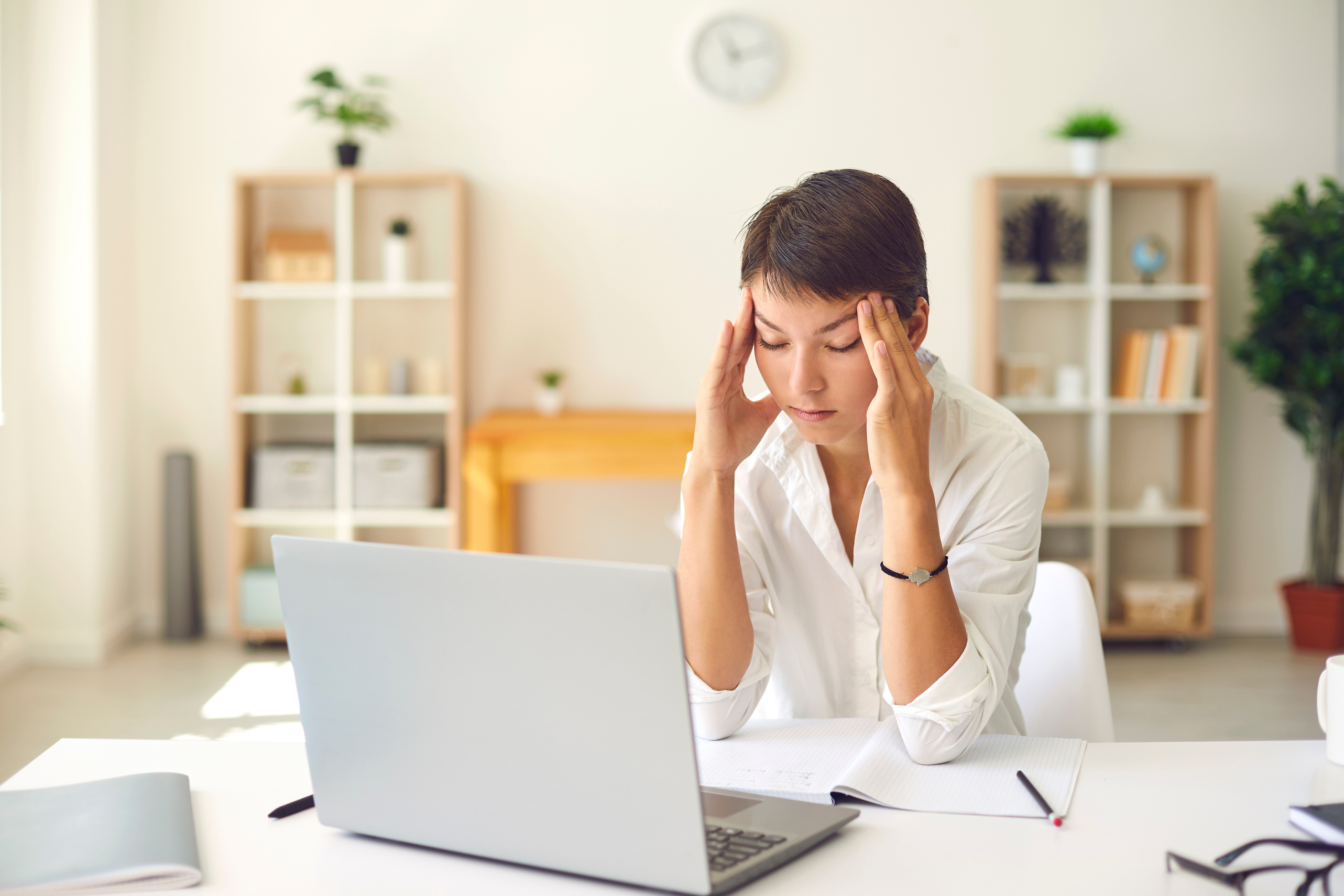 Tired Woman with Bad Headache or Blurry Vision Massaging Temples Sitting at Desk with Laptop